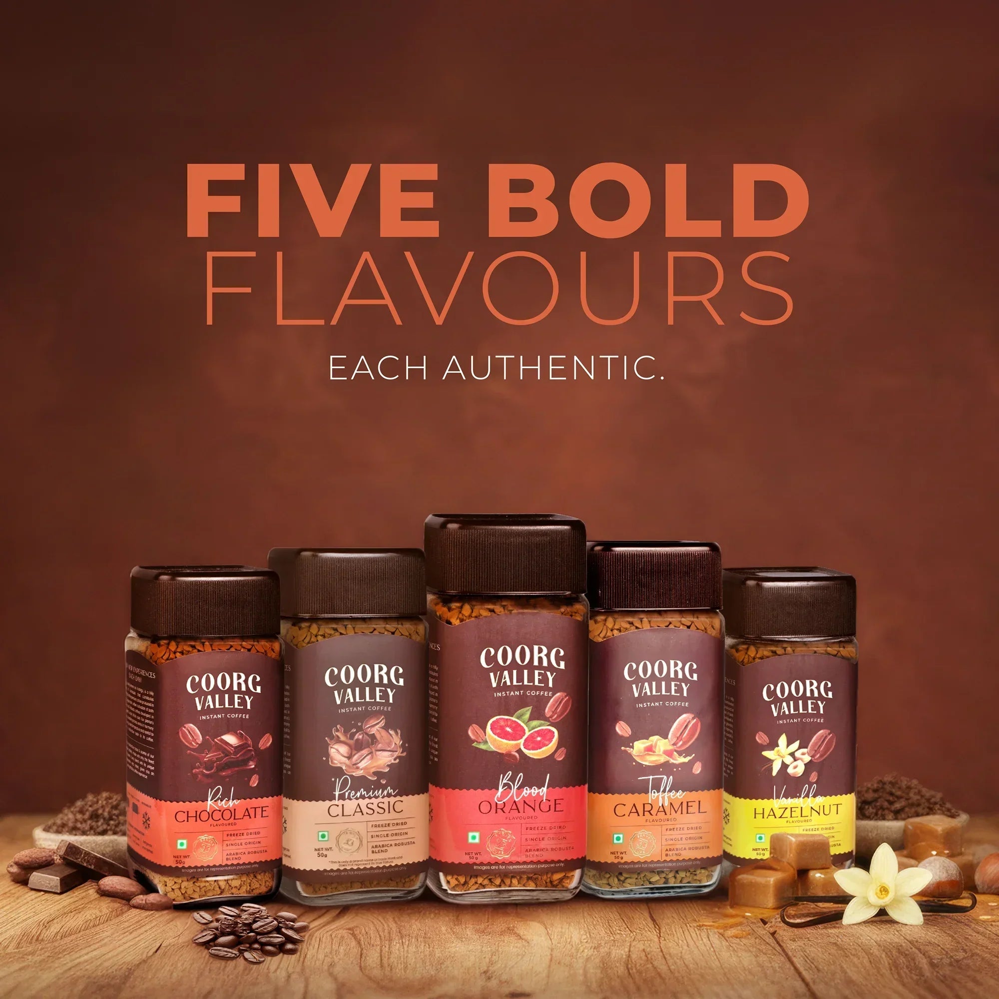 Five jars of Coorg Valley instant coffee in assorted flavors, displayed on a wooden table.