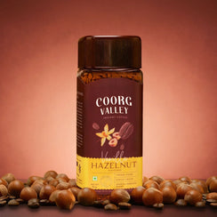 Coorg Valley Vanilla Hazelnut instant coffee jar with hazelnuts on a brown background