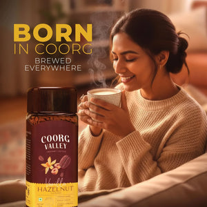 Woman enjoying a hot cup of coffee with Coorg Valley Vanilla Hazelnut instant coffee jar in focus.