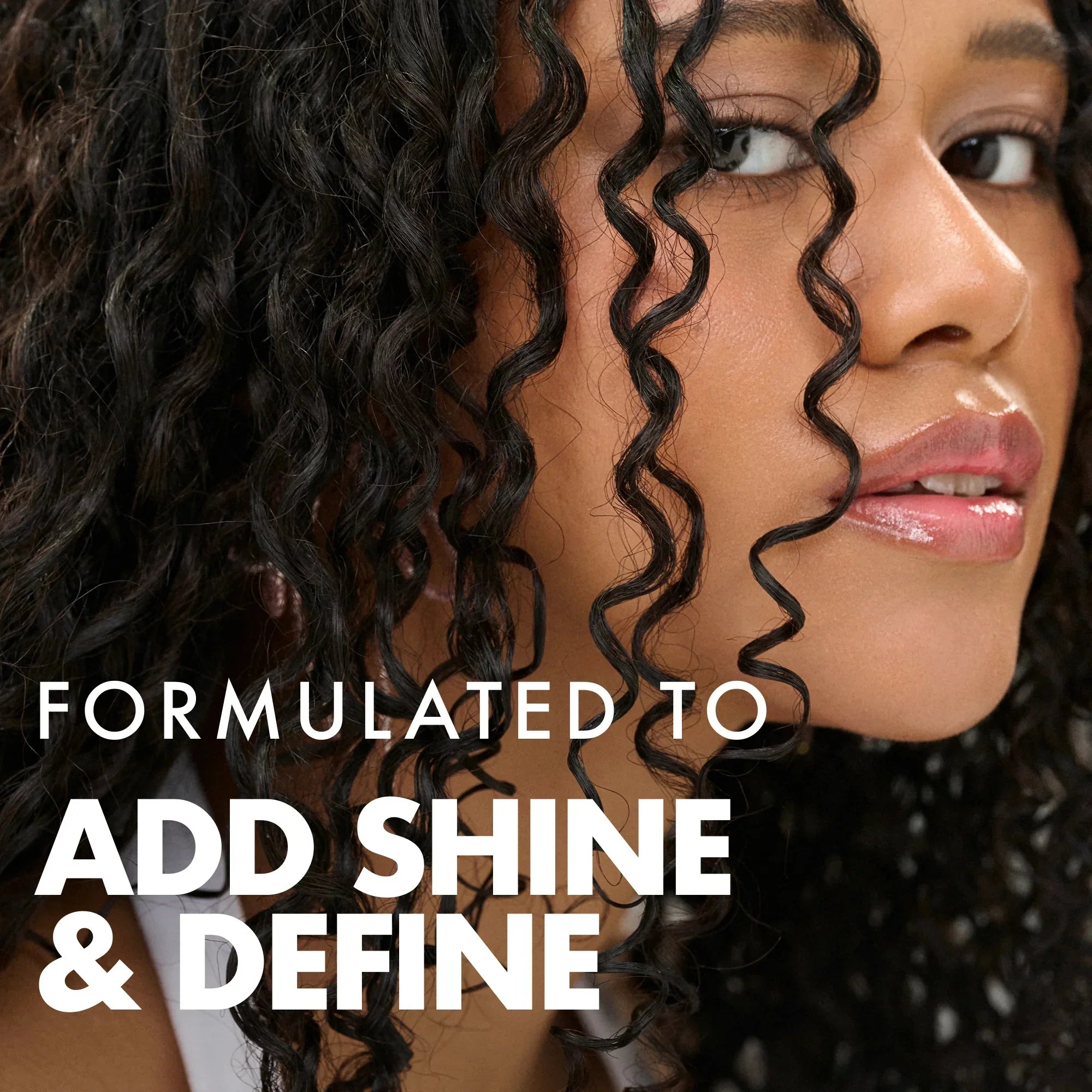 Close-up of woman with defined glossy curly hair promoting hair product to add shine and define curls