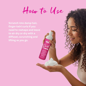 Woman with curly hair holding pink Umberto Giannini Curl Foam anti-frizz styling mousse on pink background with usage instructions