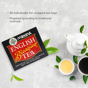 Box of English Breakfast tea bags with teapot, tea cups, and green tea leaves on a gray surface