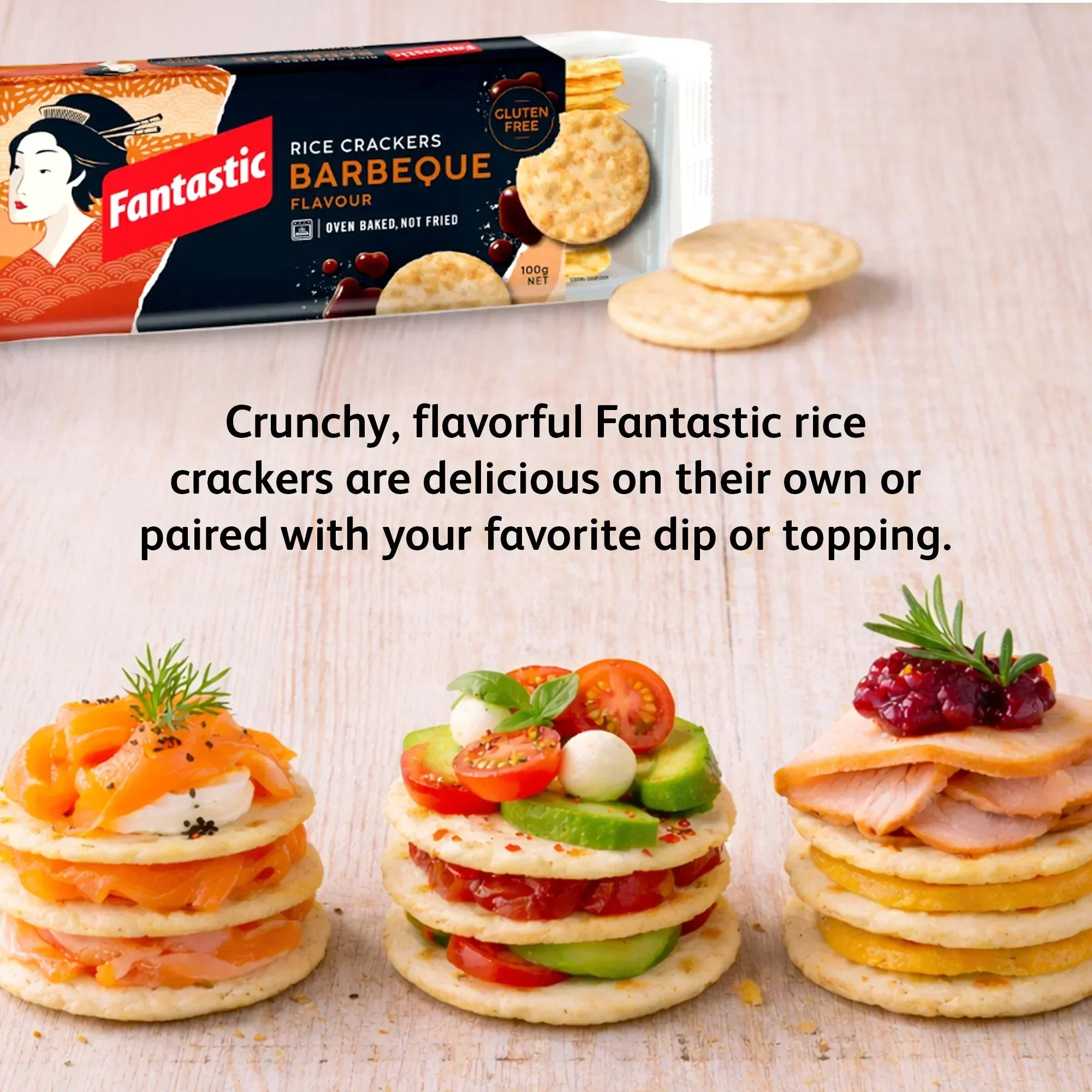 Barbeque rice crackers with gourmet toppings, tomatoes, salmon, and cheese on a wooden surface.