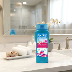 Finesse moisturizing shampoo bottle on marble bathroom counter with towels, soap, and orchid