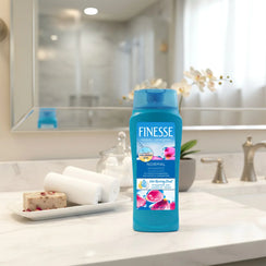 Finesse Normal shampoo bottle with hyaluronic acid on bathroom counter with towels and soap