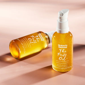 Umberto Giannini The Frizz Oil vegan hair serum bottles with pump cap on pink background