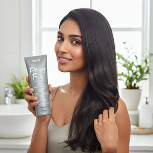 Smiling woman with long smooth black hair holding Frizz Fix shampoo tube in bright modern bathroom