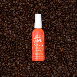 Umberto Giannini Grow Serum orange bottle on dark roasted coffee beans background, long hair serum with caffeine complex
