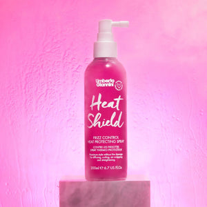 Umberto Giannini Heat Shield frizz control heat protecting spray bottle on pink background with mist