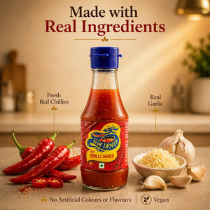 Blue Dragon hot chilli sauce bottle with fresh red chillies and garlic on kitchen counter
