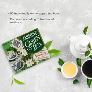 Jasmine green tea box, white teapot, two cups of tea, and green tea leaves on light background