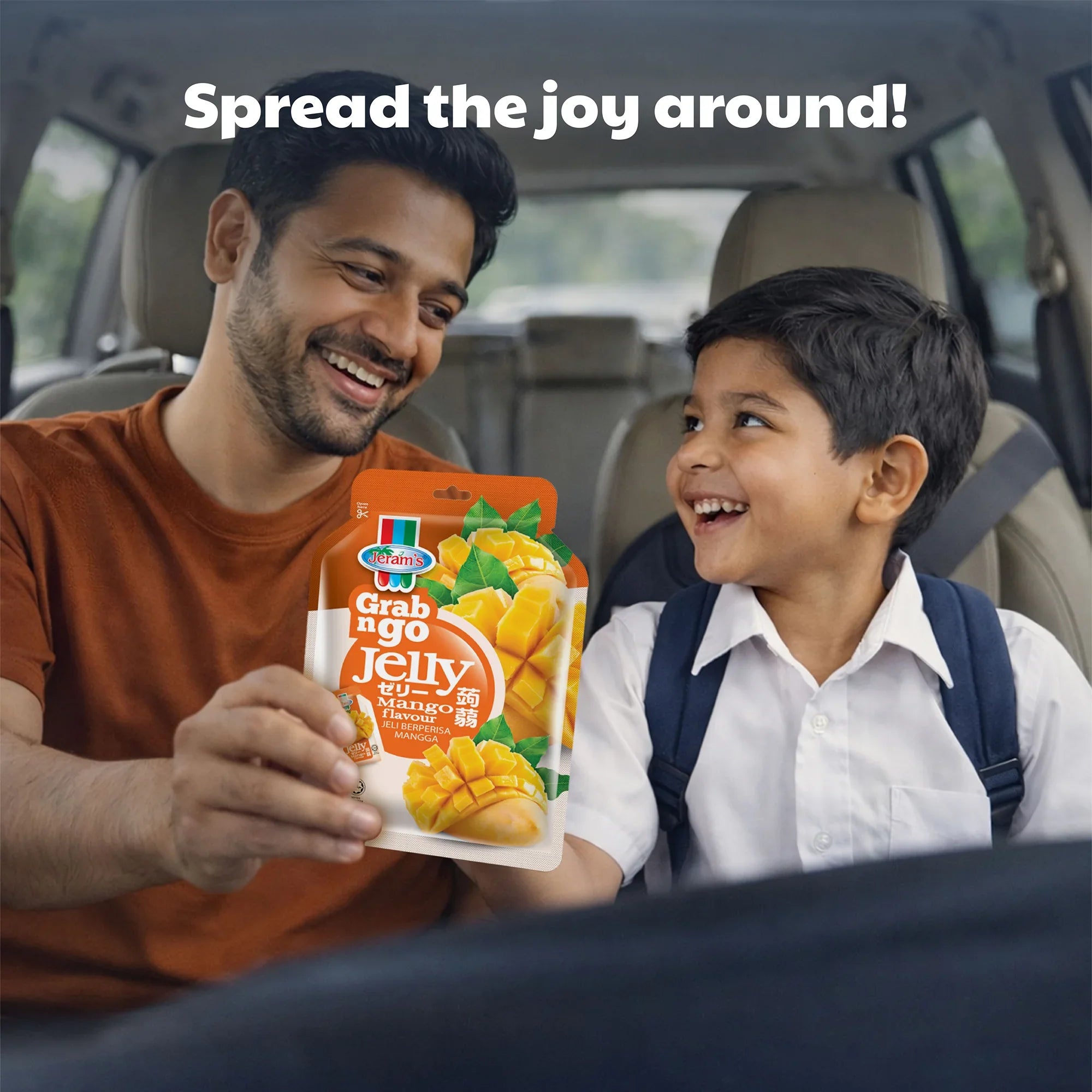 Man and child in a car smiling, holding Grab n Go mango flavoured jelly snack