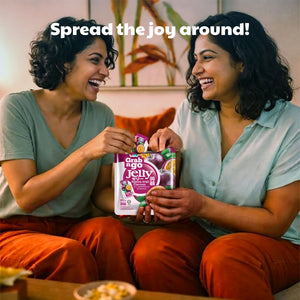 Two women smiling and sharing Grab n Go Passion Fruit Jelly snacks in a cozy living room.