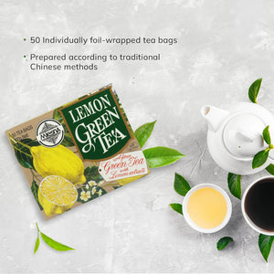 Box of lemon green tea with lemon and green tea leaves, next to a white teapot and two tea cups.