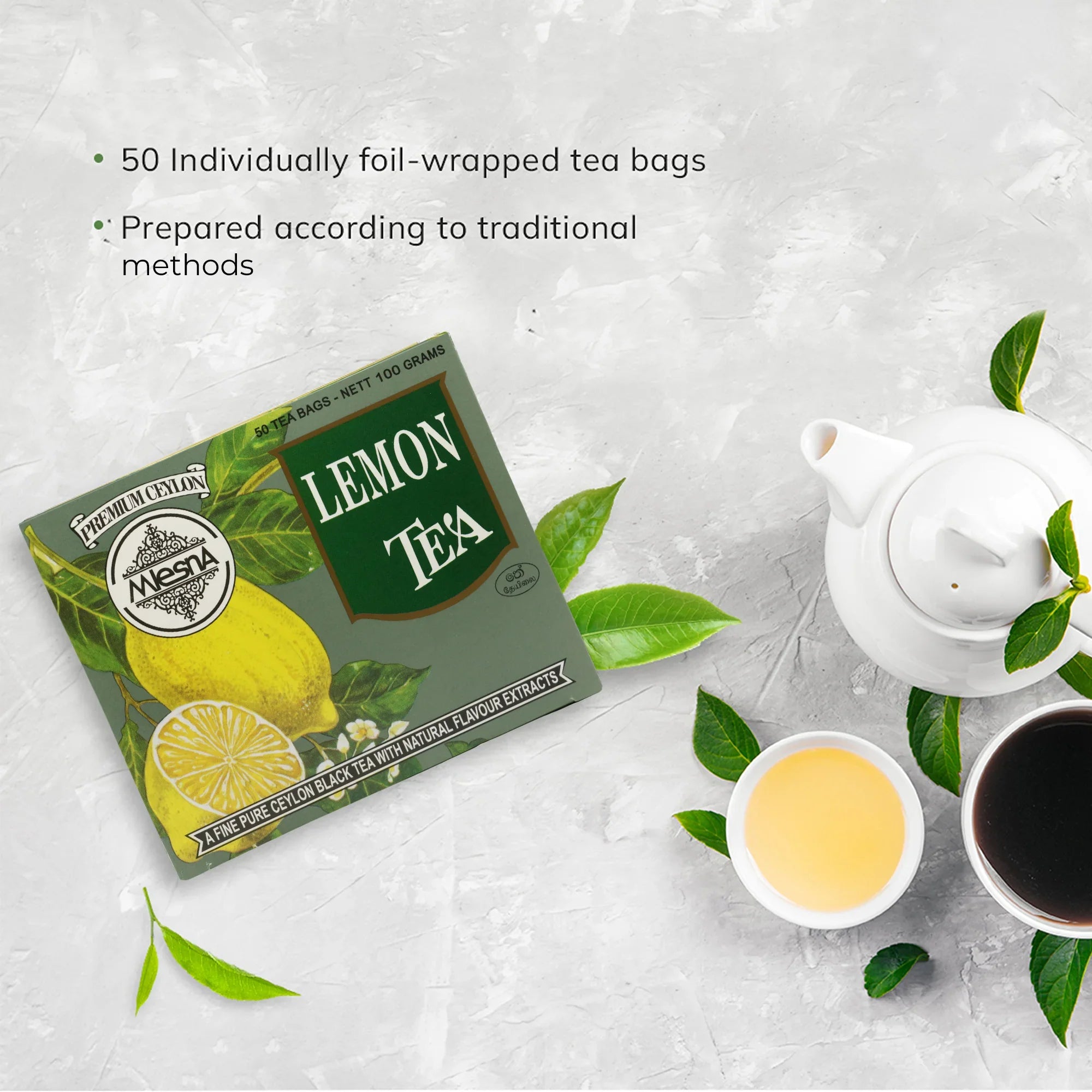 Box of lemon tea with tea cups, teapot, and fresh tea leaves on a light background