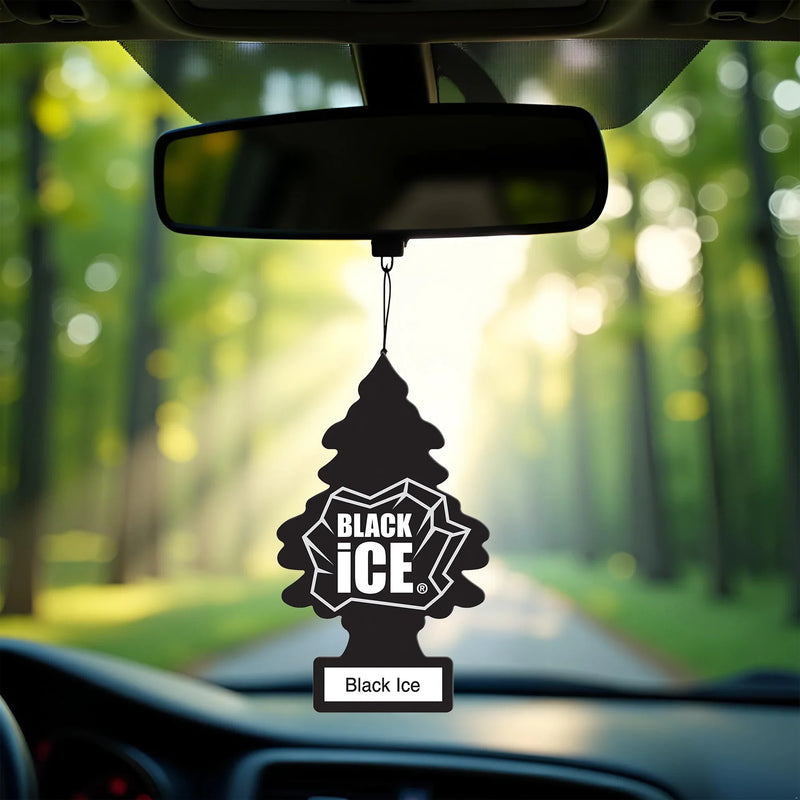 Black Ice car air freshener hanging from rearview mirror inside vehicle with sunlit forest road background