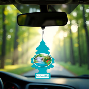 Blue Little Trees Rainforest Mist car air freshener hanging from rearview mirror with forest background