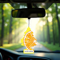 Car rearview mirror with hanging Little Trees air freshener featuring sliced lemon design in sunny forest road setting