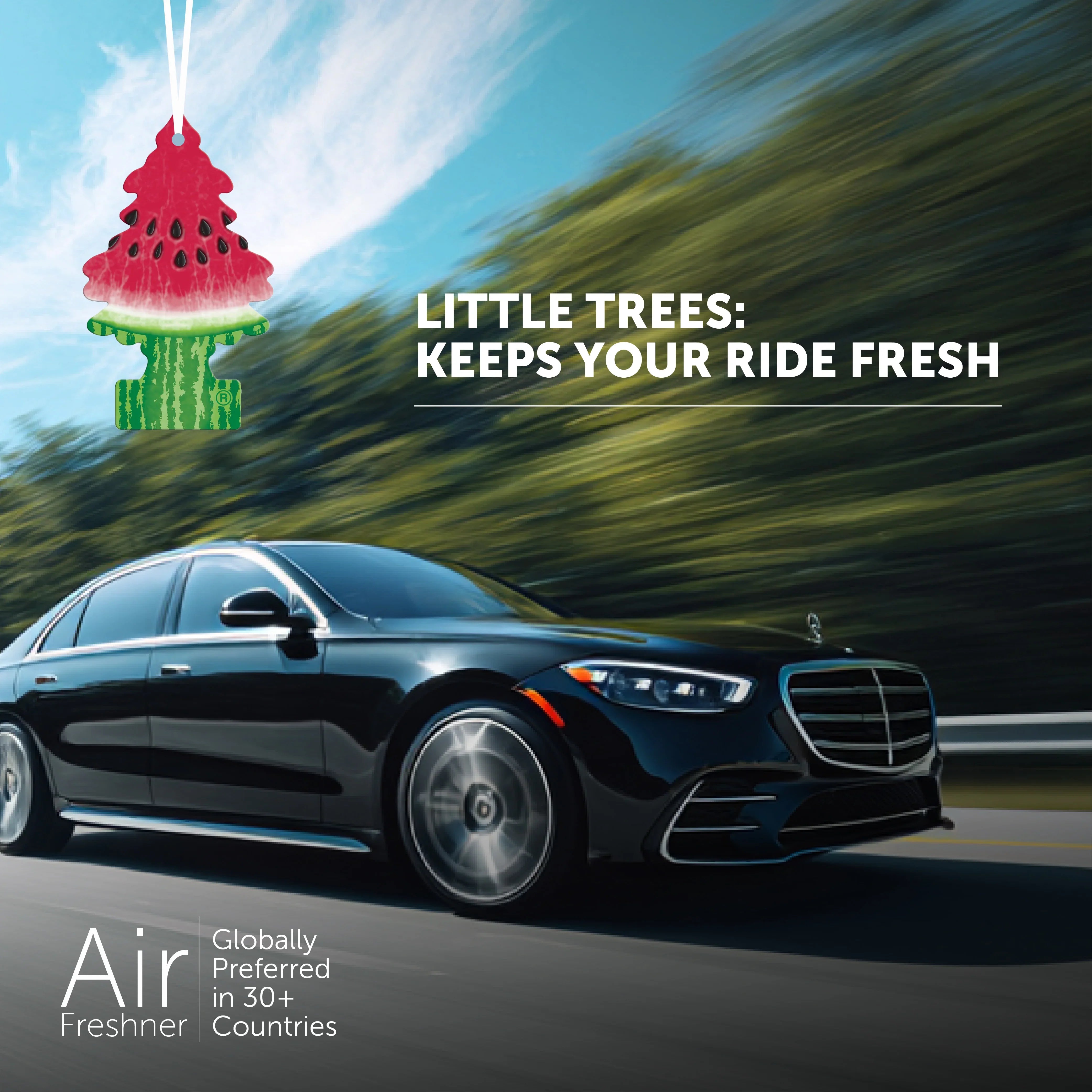 Black luxury car driving on road with hanging watermelon-scented Little Trees air freshener and fresh ride text