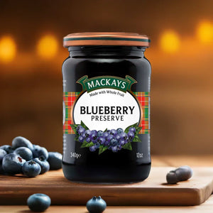 Jar of Mackays Blueberry Preserve on wooden board with fresh blueberries and warm bokeh background