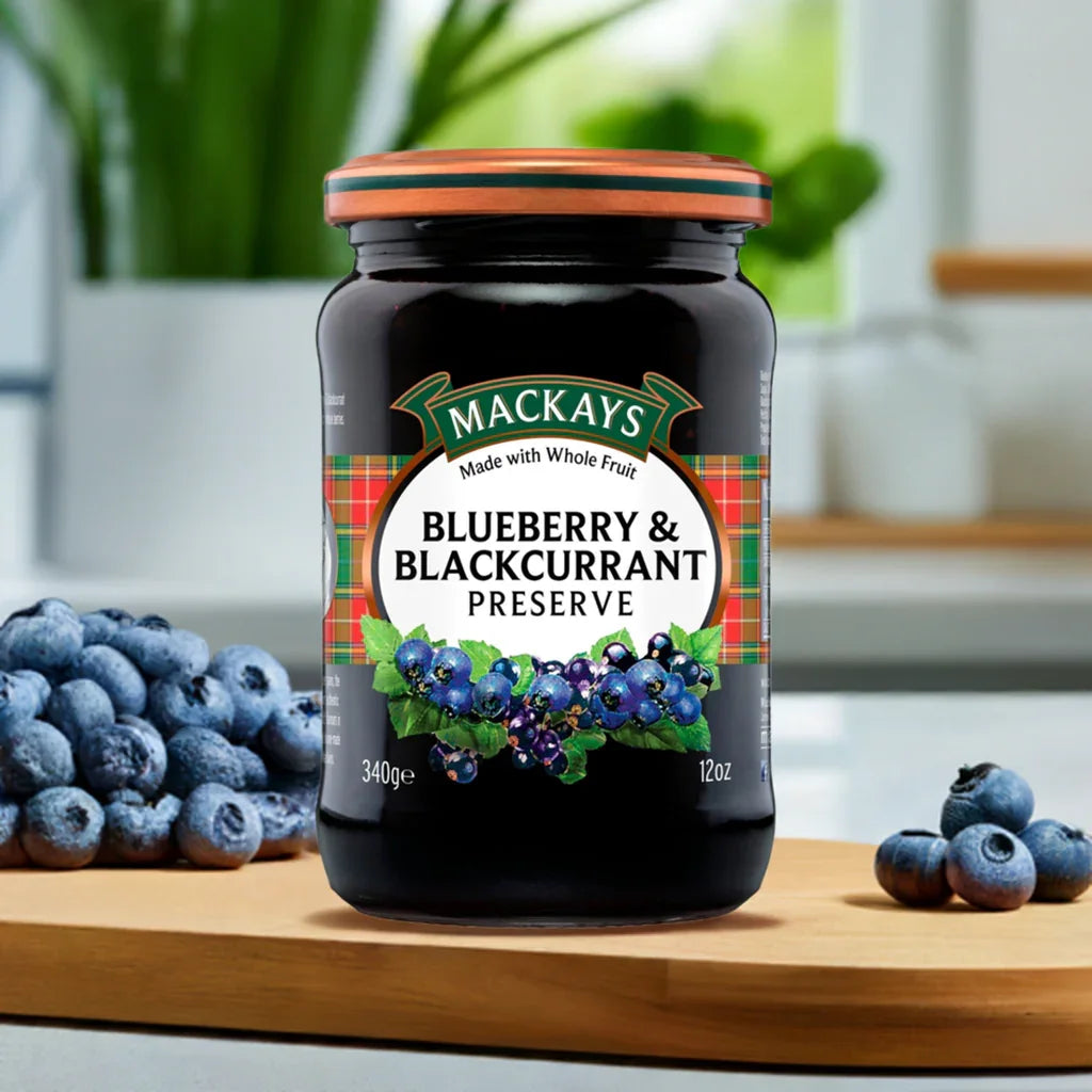 Jar of Mackays Blueberry & Blackcurrant Preserve on wooden board with fresh blueberries