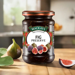 Mackays fig preserve jar on wooden surface with fresh figs and soft kitchen background