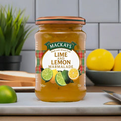 Jar of Mackays lime and lemon marmalade on kitchen counter with sliced lime and lemons nearby