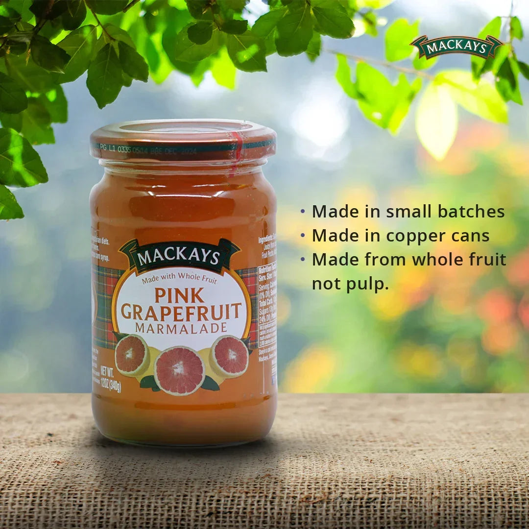 Jar of Mackays Pink Grapefruit Marmalade on a rustic surface with green leaves and sunlight background