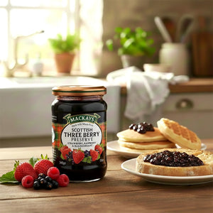 Jar of Scottish three berry preserve with berries, toast, and pancakes in a kitchen setting