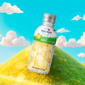 Mogu Mogu sugar free mango candy bottle with yellow candy pieces on a grassy hill background