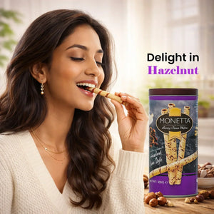 Woman enjoying hazelnut wafer stick with Monetta Luxury Cream Wafers tin and hazelnuts