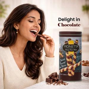 Woman enjoying chocolate cream wafer roll next to Monetta wafer tin and chocolate pieces