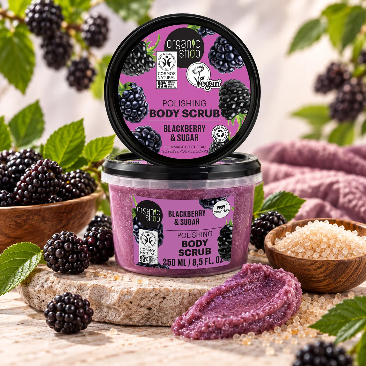 Organic Shop Blackberry & Sugar Polishing Body Scrub in a purple tub with fresh blackberries.