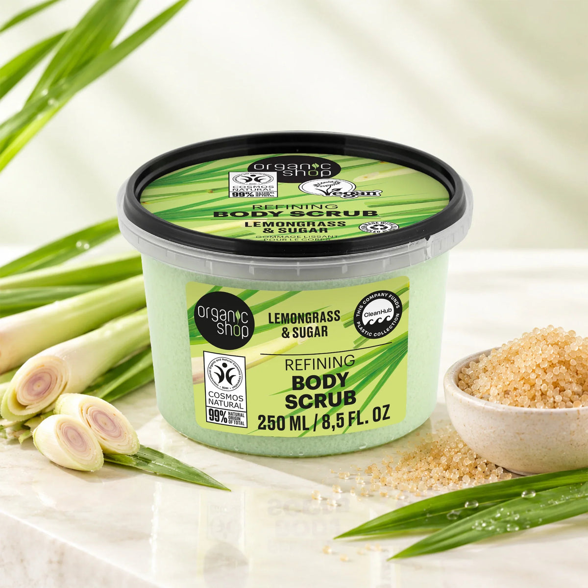 Organic Shop Lemongrass & Sugar Refining Body Scrub jar with fresh lemongrass and sugar crystals