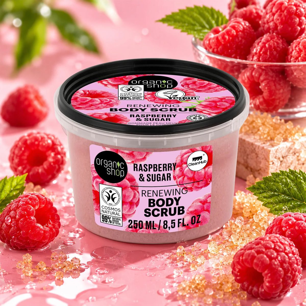 Organic Shop Raspberry and Sugar Renewing Body Scrub jar surrounded by fresh raspberries.