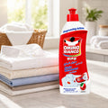 Omino Bianco Stain Remover Pre-Wash bottle with degreasing action, beside folded clothes in bright laundry room