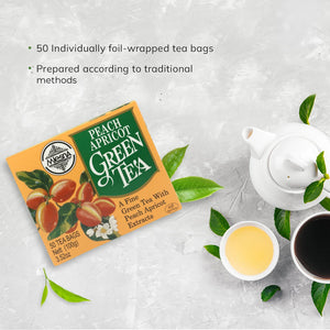 Peach apricot green tea box with teapot, tea cups, green tea leaves on light background