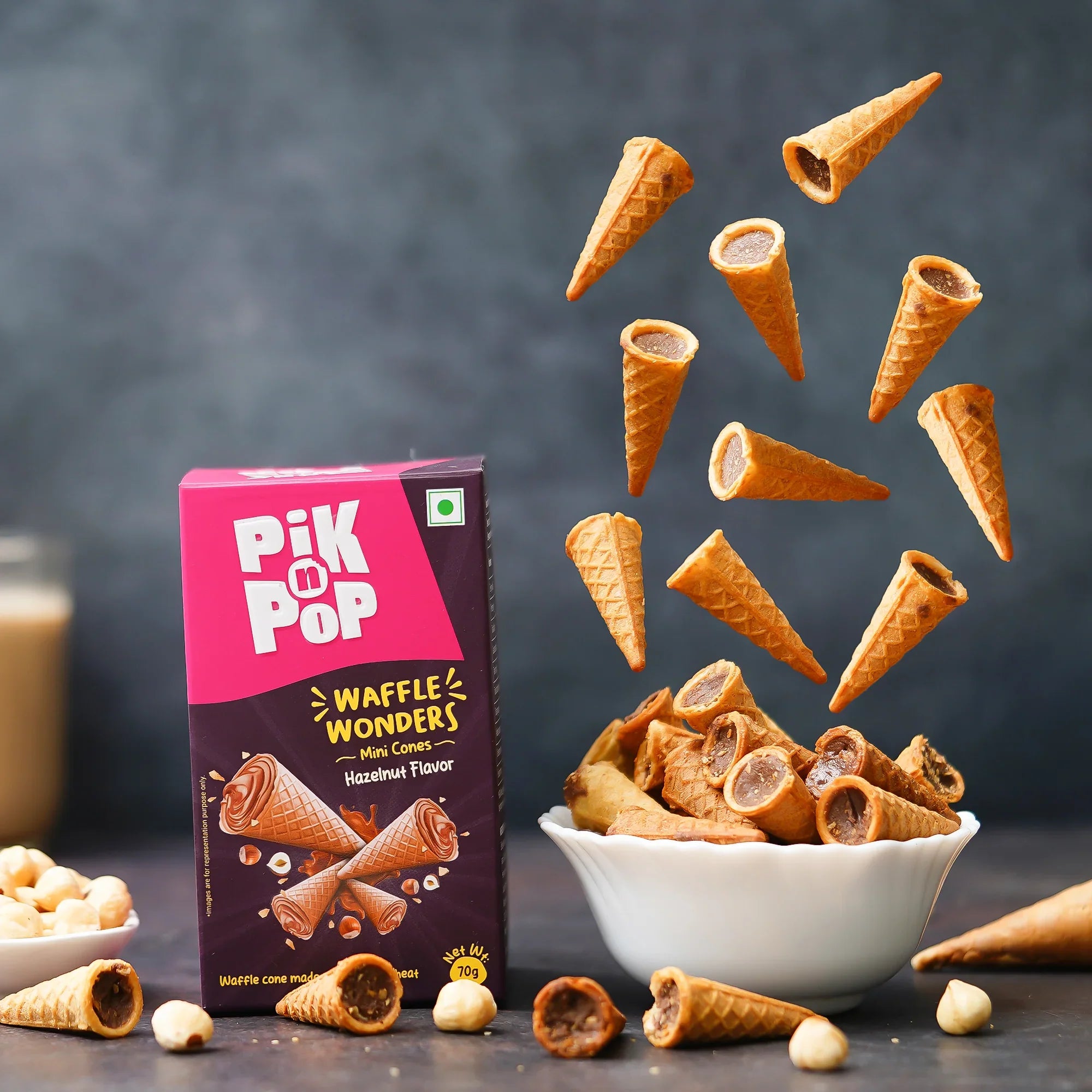 Mini hazelnut waffle cones in bowl and mid-air, Pik n Pop box, nuts on table