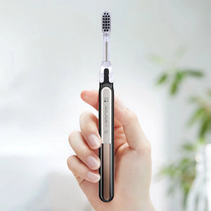 A hand holding a sleek Soladey 5 electric toothbrush with a silver and black handle.