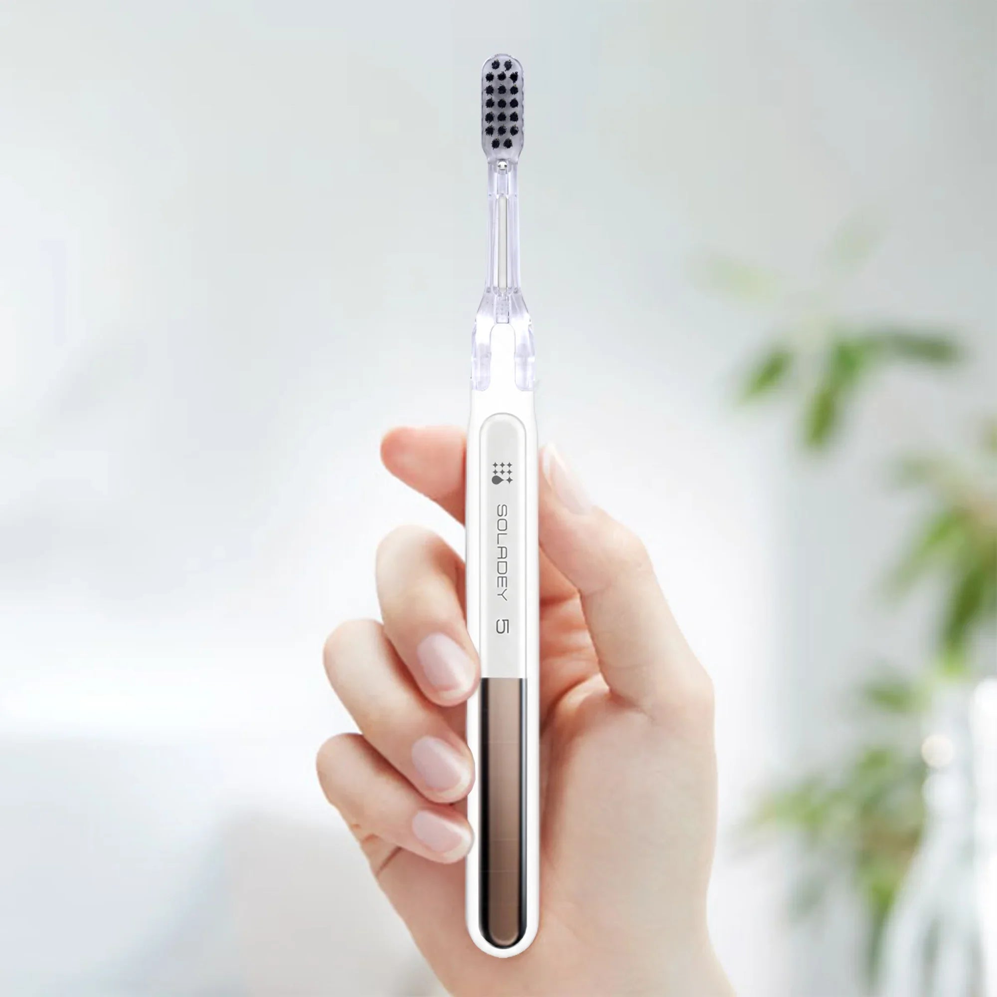 Hand holding a Soladex 5 white electric toothbrush with a black brush head.