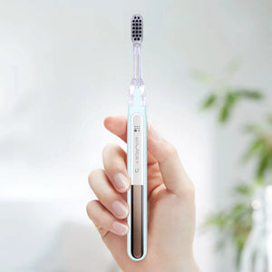 A hand holding a light blue Soladey 5 toothbrush against a soft, blurred background.