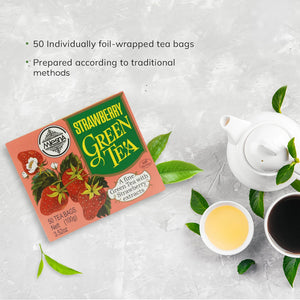 Strawberry green tea box with tea leaves, white teapot, and cups of brewed green tea on a light background.
