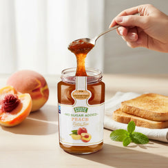 Hand holding spoon with amber peach jam from a jar labeled No Sugar Added by Stute, sliced peaches and toast on table