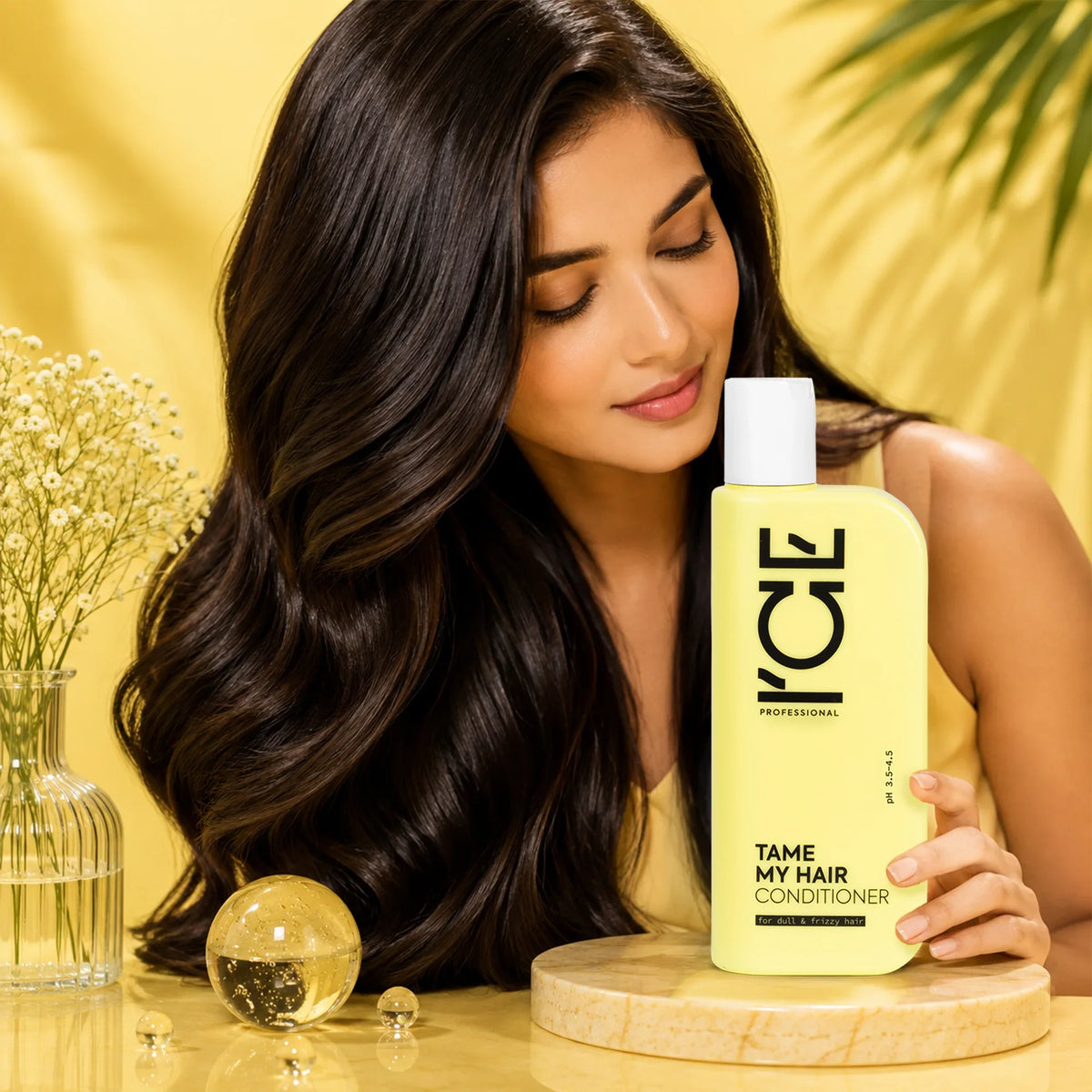 Woman with shiny wavy hair posing next to a bottle of ICE Professional Tame My Hair Conditioner.