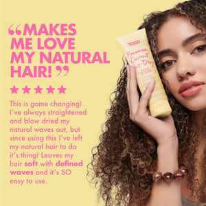 Woman holding Umberto Giannini Banana Coconut Air Dry Styling Cream with natural curly hair, hair care review