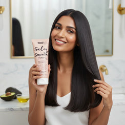 Smiling woman with long smooth hair holding Umberto Giordani Salon Smooth hair smoothing cream in modern bathroom